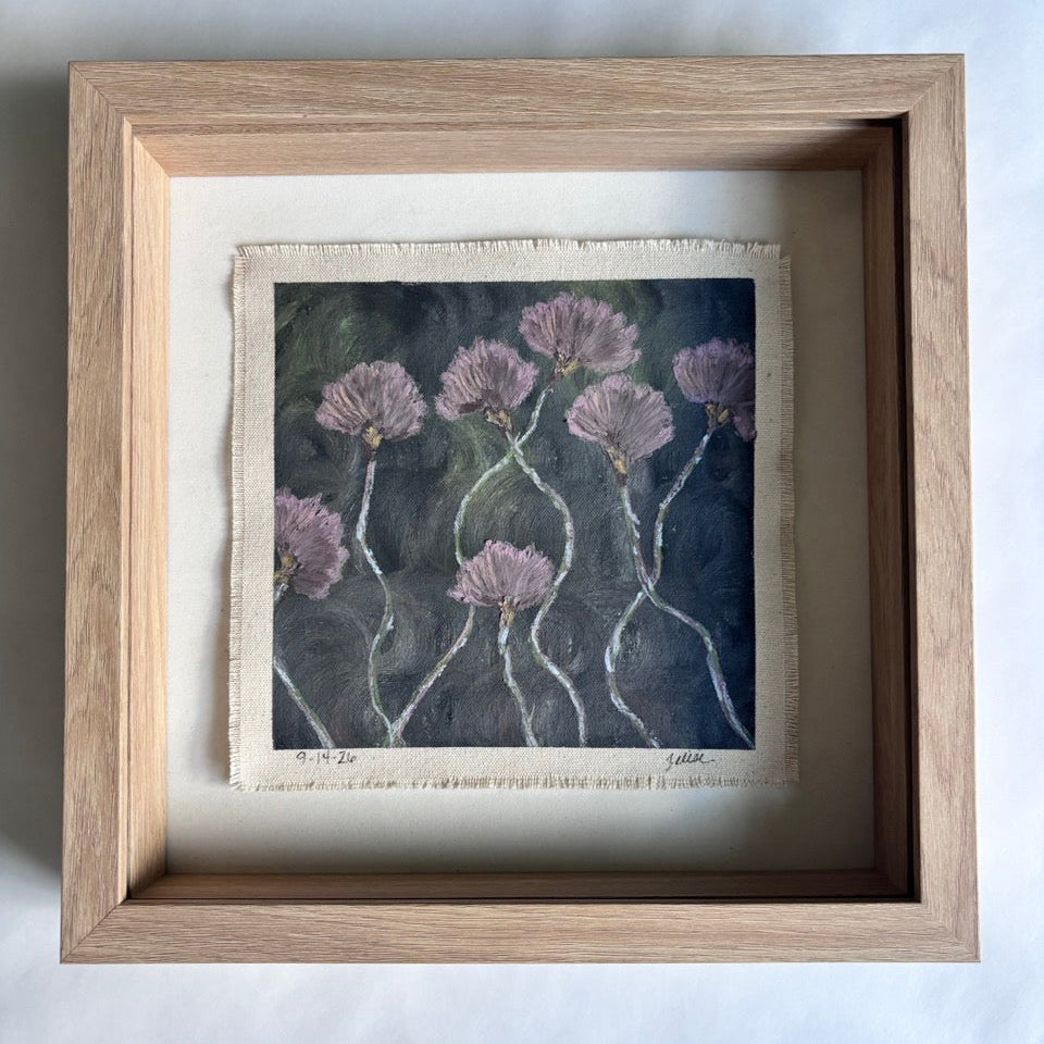 A framed painting featuring a textured painting of lavender flowers on a dark background, housed in a light oak shadowbox frame with a cream mat.